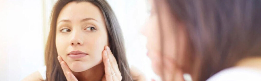 woman looking at her skin in the mirror